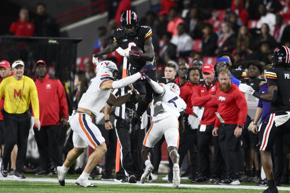 Maryland tight end Corey Dyches (2) leaps with the ball between Virginia cornerback Dre Walker (6) and linebacker James Jackson during the second half of an NCAA college football game Friday, Sept. 15, 2023, in College Park, Md. (AP Photo/Nick Wass)