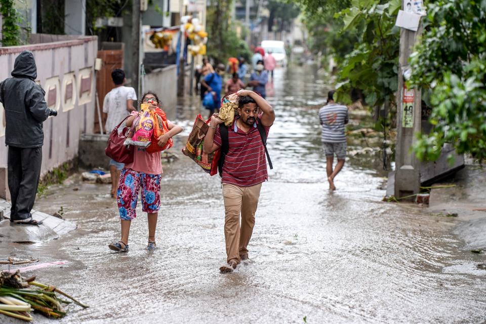 Residents carrying their belongings make their way on a flooded street following heavy rains in Hyderabad on October 14, 2020. (Photo by NOAH SEELAM / AFP) (Photo by NOAH SEELAM/AFP via Getty Images)