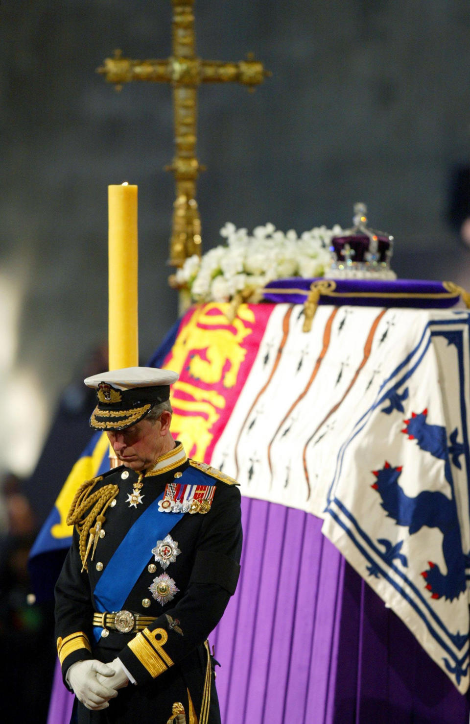 FILE - Britain's Prince Charles, the Prince of Wales, stands in front of the flag draped coffin of Queen Elizabeth, the Queen Mother, as she lies in state and is guarded at the four corners of the catafalque by her grandsons, in Westminster Hall, London Monday, April 8 2002. When Queen Elizabeth II’s grandfather, King George V, died in 1936, life in Britain is unrecognizable to people today. But despite almost a century of change, the images from the queen’s lying in state this week are almost exact copies of those from George V’s time. (Adrian Dennis/Pool Photo via AP, File)