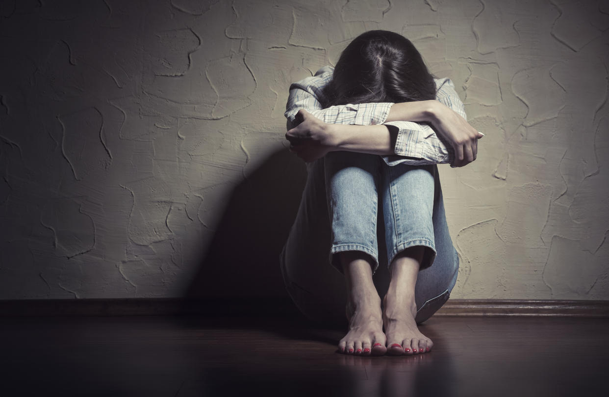 Woman crouching against wall.