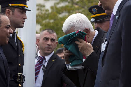 Palestinian President Mahmoud Abbas kisses a Palestinian flag before raising it during United Nations General Assembly at the United Nations in Manhattan, September 30, 2015. REUTERS/Andrew Kelly