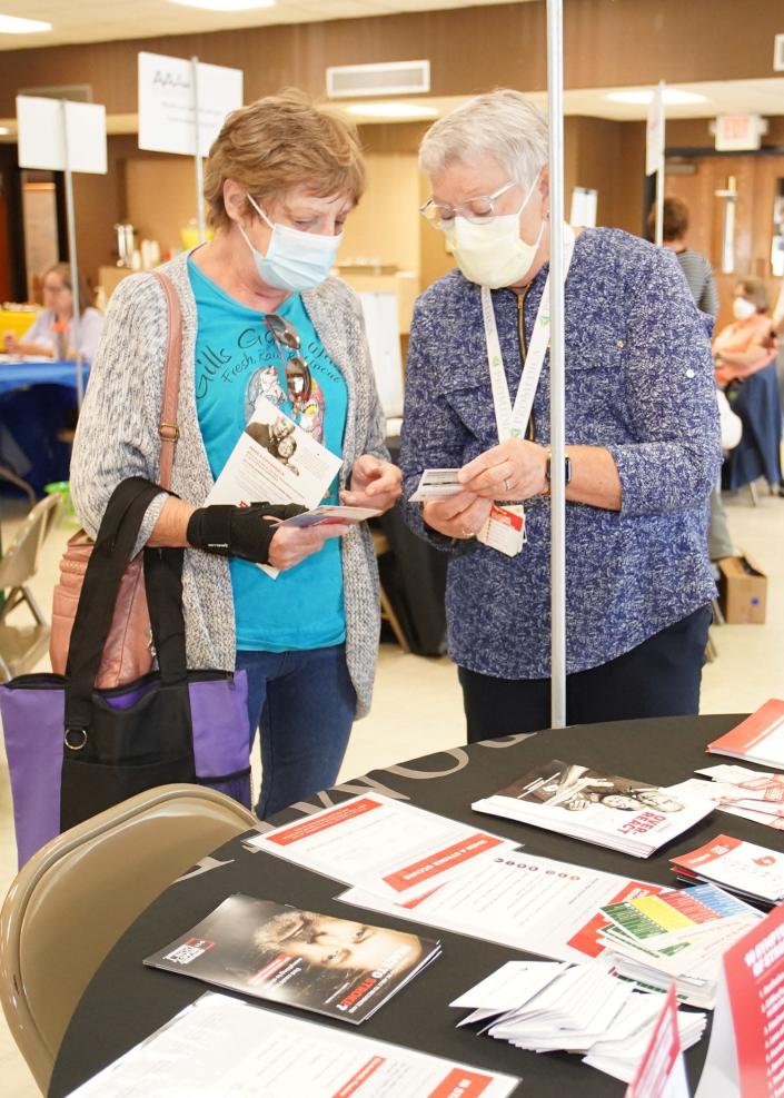 Eileen Comar of Adrian, left, speaks with Michelle Deeter of ProMedica Charles and Virginia Hickman Hospital about stroke and trauma awareness during Thursday's Health Check clinic in Adrian at the Fr. Louis Komorowski Activities Center on the St. Mary’s campus of Holy Family Parish.