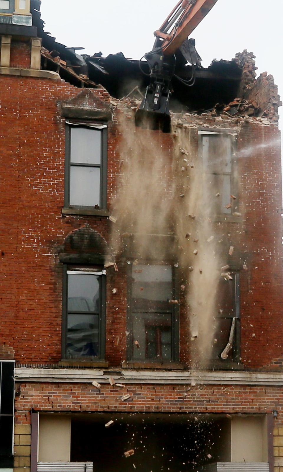 Debris falls from the top of 14 Lincoln Way E as the building comes down in Massillon on Sunday. Crews worked to demolish the buildings at 14 Lincoln Way E and 20 Lincoln Way E.