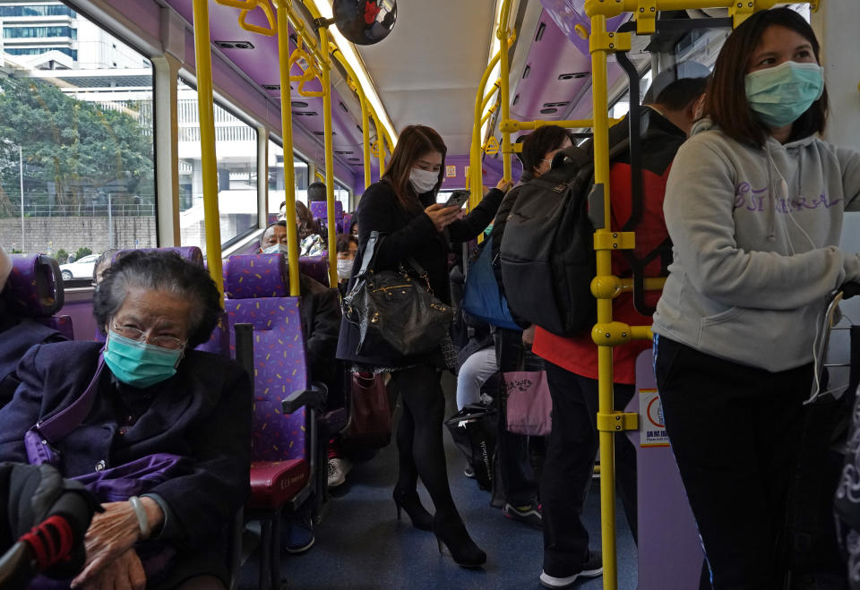 People wear protective face masks in a bus in Hong Kong, Tuesday, Feb. 4, 2020. Hong Kong on Tuesday reported its first death from a new virus, a man who had traveled from the mainland city of Wuhan that has been the epicenter of the outbreak. (AP Photo/Vincent Yu)