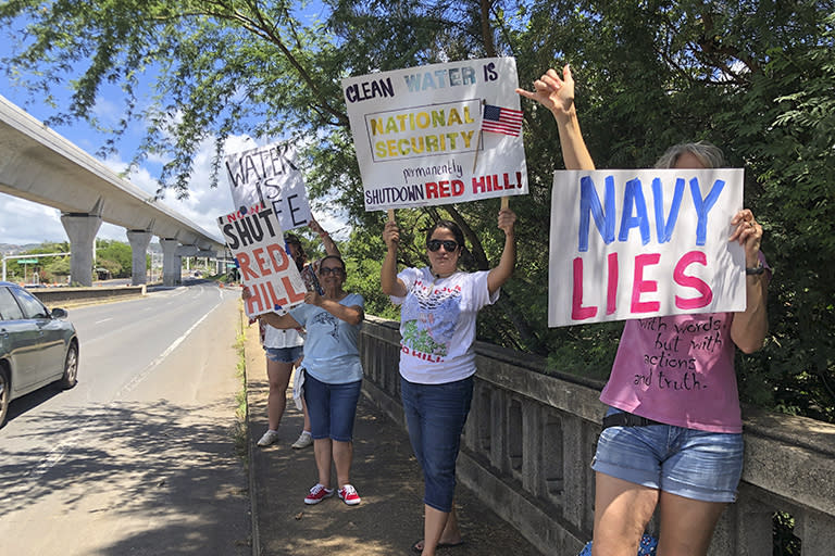 Protestors upset with the Department of Defense's response to the leak of jet fuel into the water supply hold signs outside the gate at Joint Base Pearl Harbor-Hickam, Hawaii, Friday, Sept. 30, 2022. (AP Photo/Audrey McAvoy)