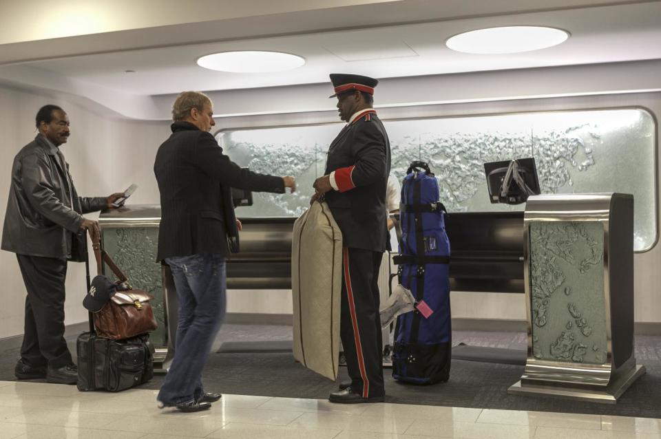 In this Thursday, March 14, 2013 photo,Singer and songwriter Michael Bolton, middle, is assisted by skycap Frederick Pearson, right, as he arrives at American Airlines Flagship Check-in terminal at Los Angeles International Airport, LAX. American's Flagship Check-in service, a VIP discreet and expedited check-in process offers personal access to agents for assistance with check-in and bag check, and a separate security line when flying through LAX and now Miami International Airport. (AP Photo/Damian Dovarganes)