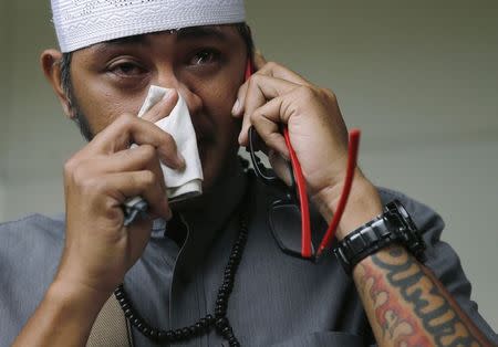 An Indonesian man, whose wife is a passenger onboard the missing AirAsia flight QZ8501, makes a phone call at a waiting area in Juanda International Airport, Surabaya December 29, 2014. REUTERS/Beawiharta