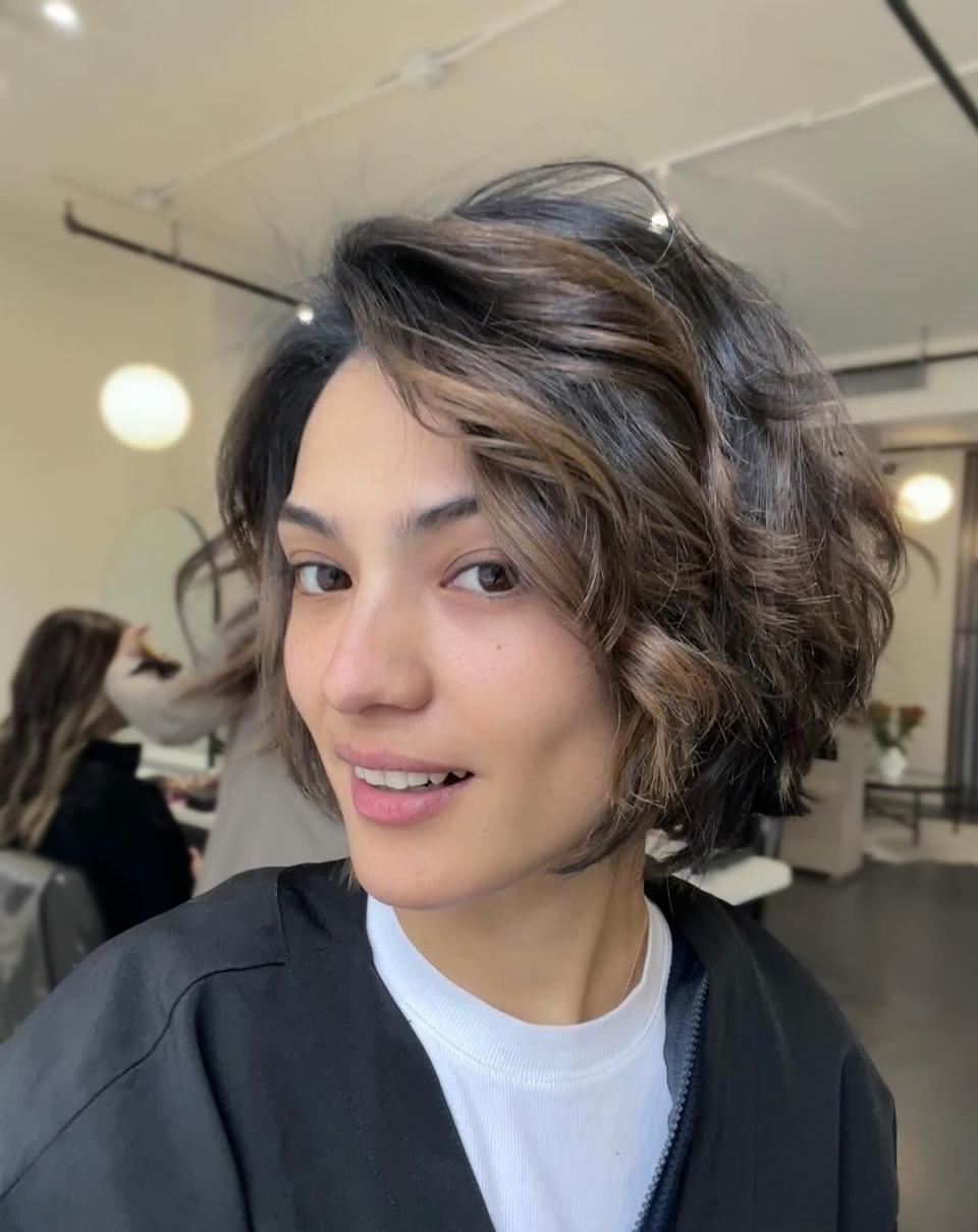 A woman with short dark hair and highlights smiles at the camera.