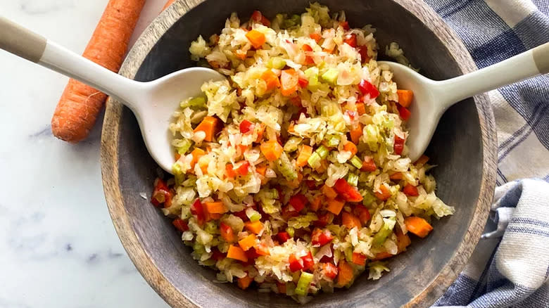 Sauerkraut with vegetables in salad bowl with serving utensils