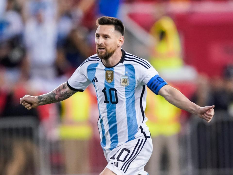 Lionel Messi runs with his arms out to sides in celebration during an Argentina soccer match.