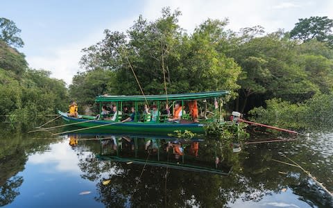 A group of tourists tries piranha fishing from a boat - Credit: iStock