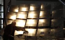 A man looks at a sun mirror technology booth during the opening day of the International Trade Fair in Munich March 14, 2012.