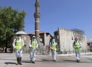 Municipality workers disinfect the courtyard of historical Haci Bayram Mosque, in Ankara, Turkey, Thursday, May 28, 2020. Turkish authorities prepare mosques for communal prayers at limited capacity, observing social distancing rules, starting with Friday prayers since mosques shut down back in March; worshippers supposed to pray outside in mosque courtyards.( AP Photo/Ali Unal)