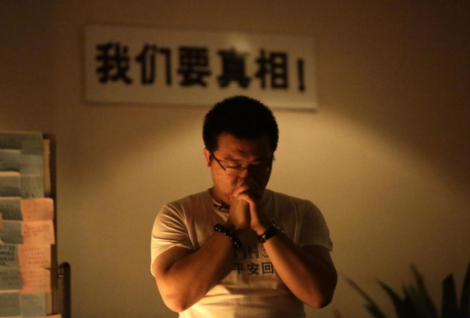 A relative of a passenger onboard Malaysia Airlines Flight MH370 prays in front of a placard at a praying room in Beijing