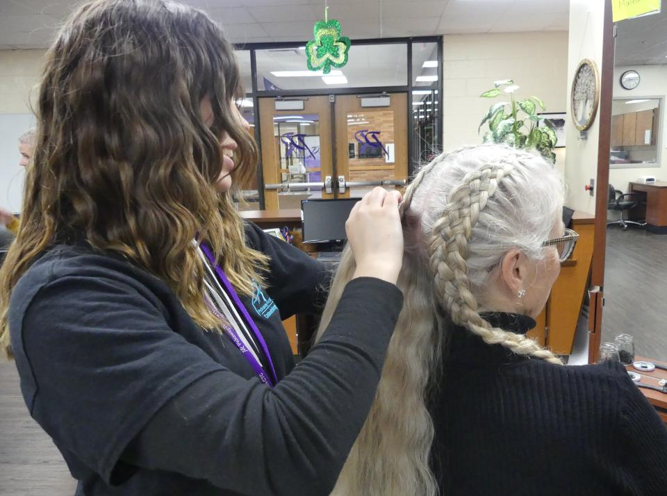 Kaitlyn McDowell, a student in the cosmetology program braids Stephanie Jones's hair.