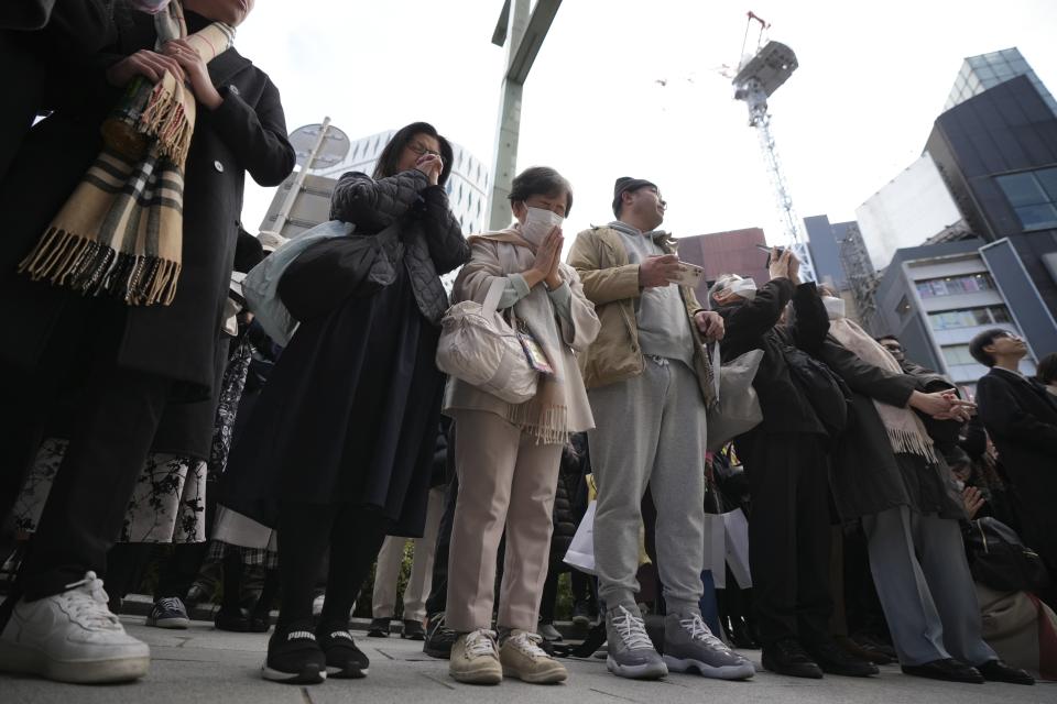 Bystanders pray when an annual tribute started at 2:46 p.m. for the victims of a 2011 disaster Monday, March 11, 2024, in Tokyo. Japan on Monday marked the 13th anniversary of the massive earthquake, tsunami and nuclear disaster that struck Japan's northeastern coast. (AP Photo/Eugene Hoshiko)