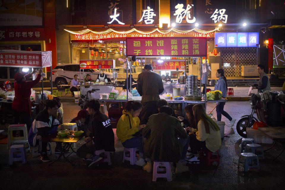 In this March 27, 2019, photo, people eat at an outdoor night market in Xi'an, northwestern China's Shaanxi Province, similar to one at which Yin Hao, who also goes by Yin Qiang, was injured during a fight that led to his initial prescription for Tylox. Officially, pain pill abuse is an American problem, not a Chinese one. But people in China have fallen into opioid abuse the same way many Americans did, through a doctor's prescription. And despite China's strict regulations, online trafficking networks, which facilitated the spread of opioids in the U.S., also exist in China. (AP Photo/Mark Schiefelbein)