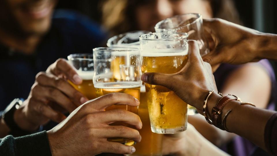 Several people clink beer glasses. 