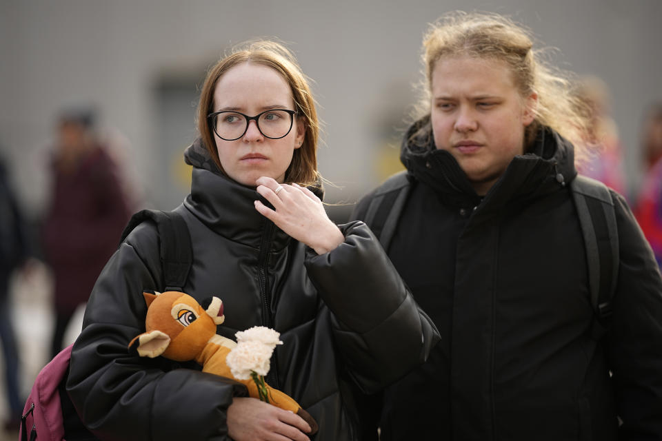 A woman carries flower and a toy to place them at a makeshift memorial in front of the Crocus City Hall on the western outskirts of Moscow, Russia, Tuesday, March 26, 2024. Russian state news agency Tass says 22 victims of the concert hall attack that killed more than 130 people remain in serious condition in the hospital. (AP Photo/Alexander Zemlianichenko)