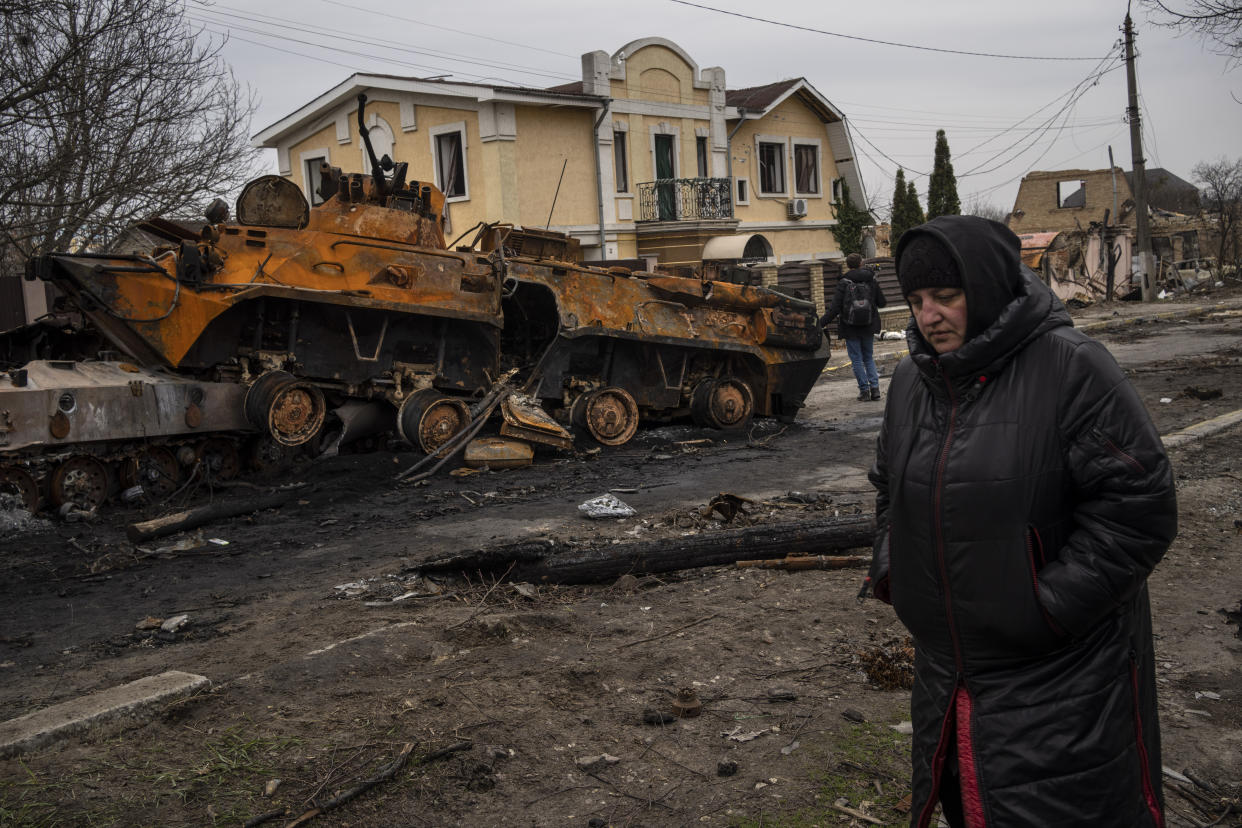 A woman walks next to a destroyed Russian armor vehicle in Bucha, in the outskirts of Kyiv, Ukraine, Tuesday, April 5, 2022. Ukraine’s president plans to address the U.N.’s most powerful body after even more grisly evidence emerged of civilian massacres in areas that Russian forces recently left. (AP Photo/Rodrigo Abd)