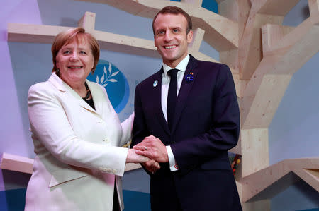 German Chancellor Angela Merkel and French President Emmanuel Macron hold hands after leaving books at the peace library at the Paris Peace Forum as part of the commemoration ceremony for Armistice Day, 100 years after the end of the First World War, in Paris, France, November 11, 2018. REUTERS/Gonzalo Fuentes/Pool