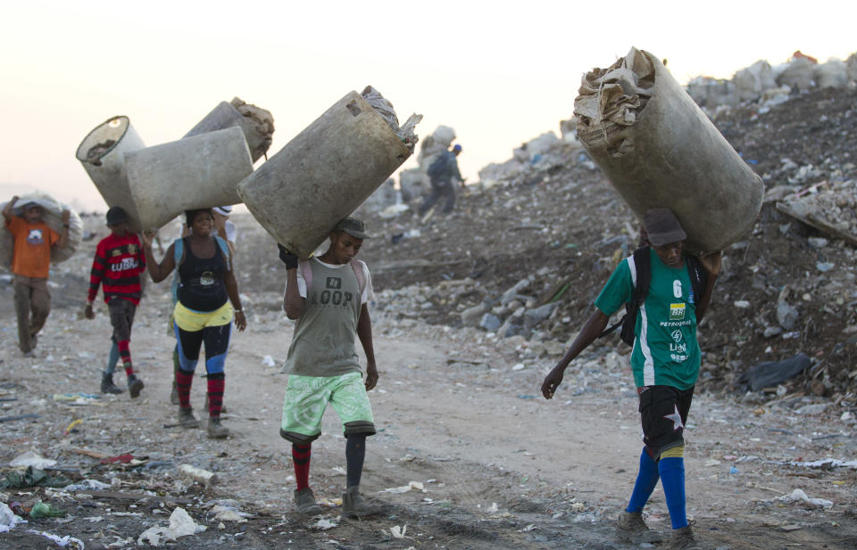 In this May 29, 2012 photo, people arrive for a day of work to collect recyclable materials at Jardim Gramacho, one of the world's largest open-air landfills, in Rio de Janeiro, Brazil. Jardim Gramacho, a vast, seaside mountain of trash where thousands of people made a living sorting through the debris by hand, is closing after three decades in service. (AP Photo/Victor R. Caivano)