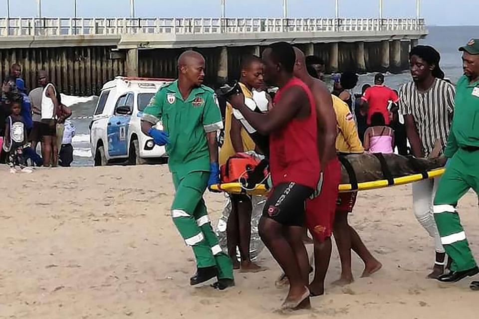 Paramedics carry a person on a stretcher on the Bay of Plenty Beach in Durban, South Africa, . South Africa's coastal city of Durban has closed its North Beach after three people died when they were caught in a freak wave.