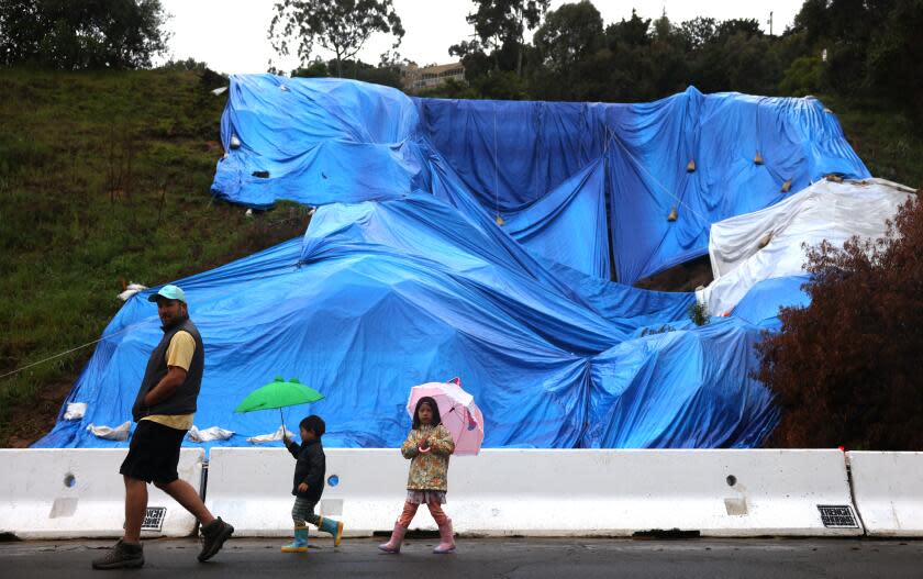 TORRANCE-CA-MARCH 30, 2024: Brian Butts and his children Carl and Abigale walk past a mudslide from a previous storm on Vista Largo in Torrance on March 30, 2024. (Christina House / Los Angeles Times)