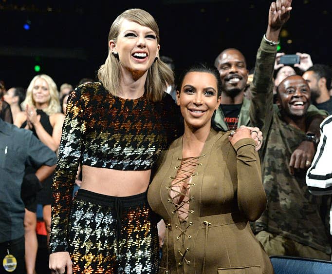 Two women smiling, one in a sequined two-piece outfit and the other in a laced-front jumpsuit, at an event