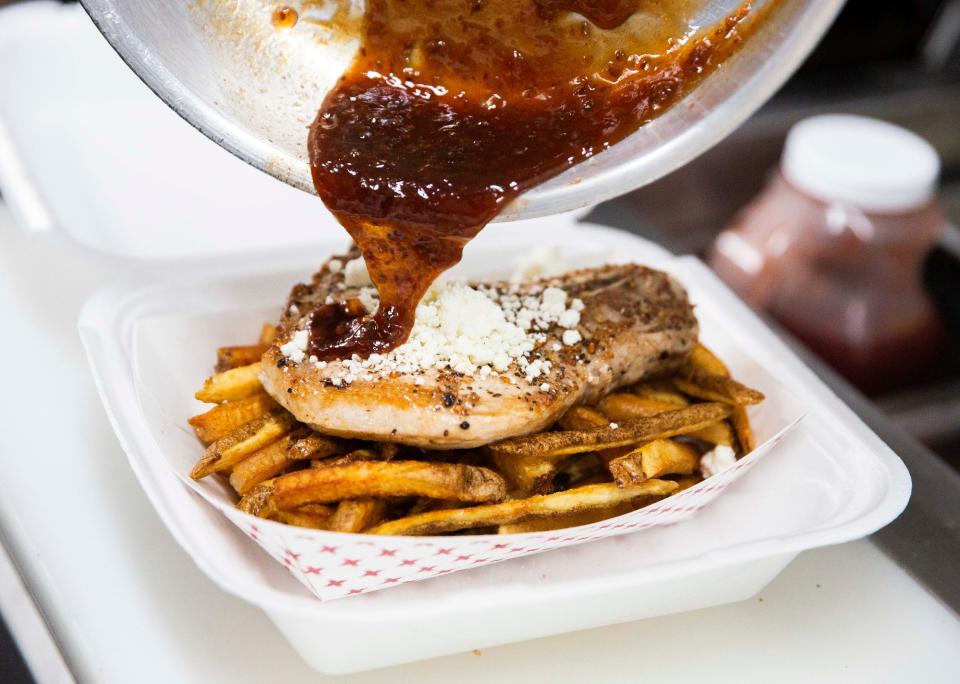 Ryan Kida pours raspberry chipotle sauce on a freshly made pork chop on the Yabo food truck at the Point Ybel Brewing Company, on Wednesday, May 11, 2022 in Fort Myers, Fla.