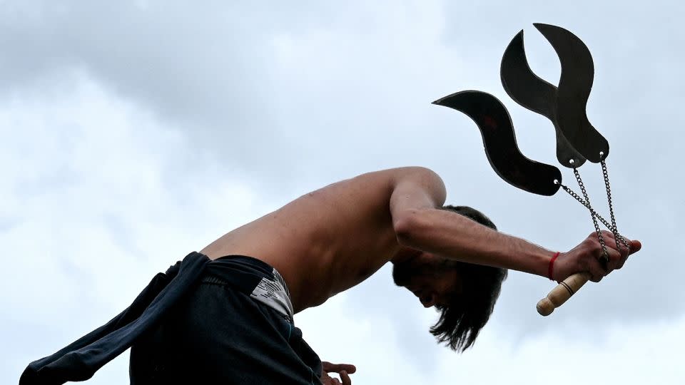 A Shiite Muslim self-flagellates with curved knives on chains during an Ashura procession in Bengaluru, India. - Idrees Mohammed/AFP/Getty Images