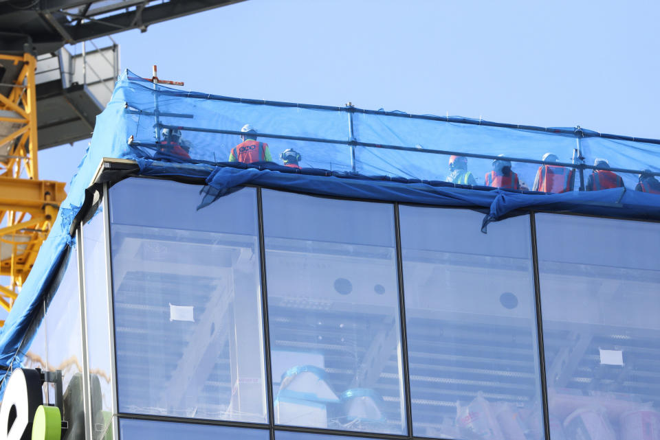 Construction workers shelter on a roof top following a shooting in the central business district in Auckland, New Zealand, Thursday, July 20, 2023. A gunman killed and injured people at a construction site in New Zealand’s largest city, as the nation prepared to host games in the FIFA Women’s World Cup soccer tournament, authorities said. (Michael Craig/New Zealand Herald via AP)