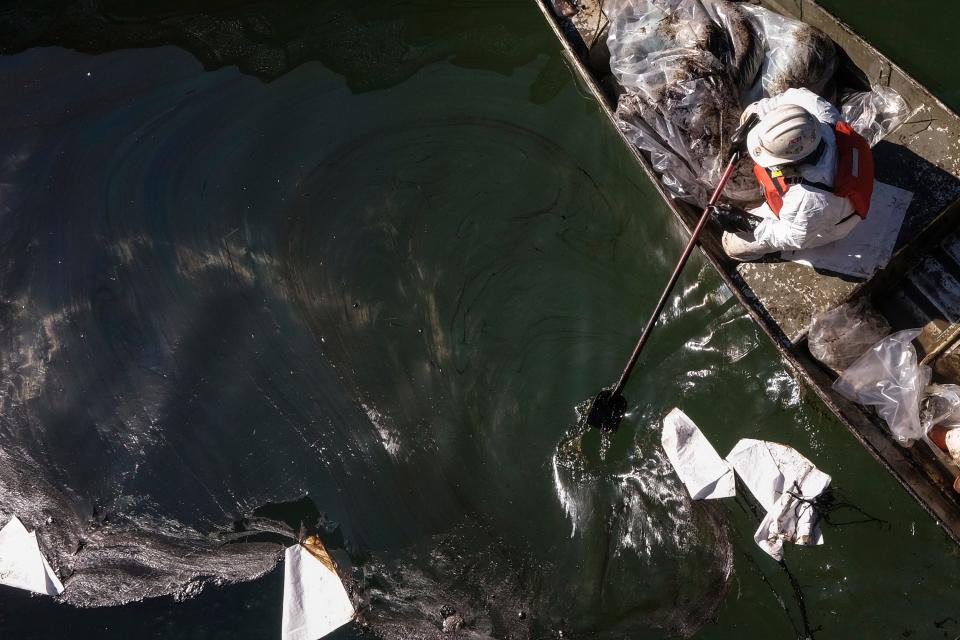 A worker in a protective suit cleans an inlet to the Talbert Marsh after an oil spill in Huntington Beach, Calif., on Oct. 5.