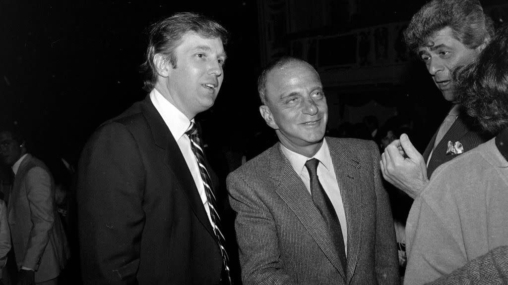 roy cohn shaking a hand as donald trump stands to his right smiling