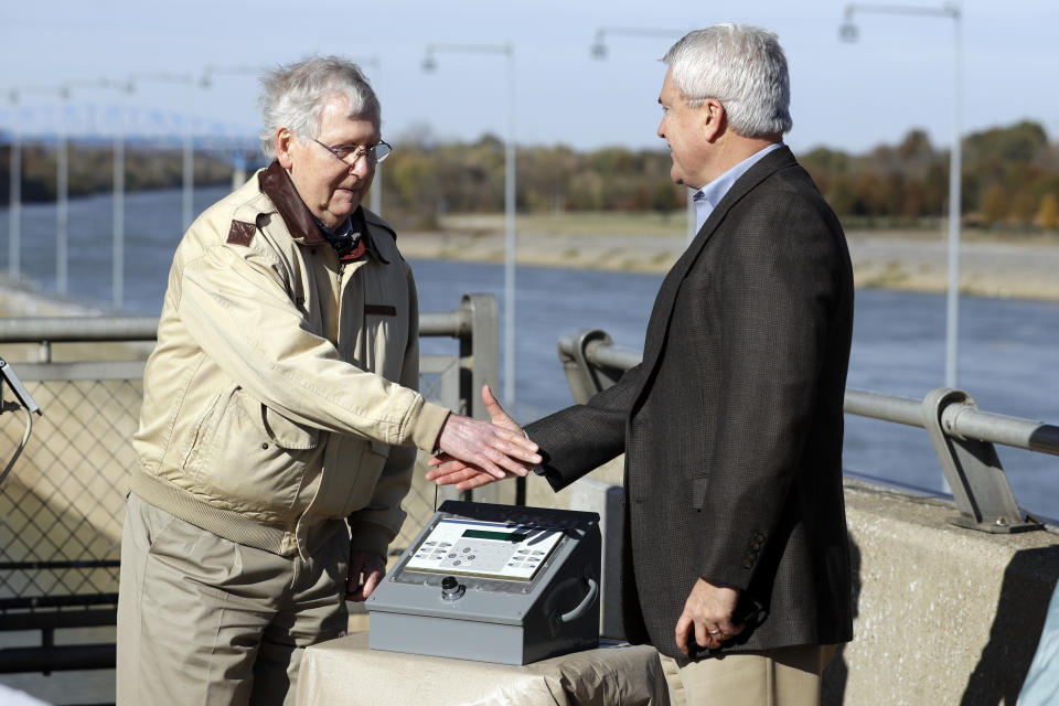 Sen. Mitch McConnell, R-Ky., left, and Rep. James Comer, R-Ky., shake hands after pressing the power button for a bio-acoustic fish fence at the Barkley Lock and Dam where the Cumberland River meets Lake Barkley Friday, Nov. 8, 2019, in Grand Rivers, Ky. The noise-making, bubbling barrier has been installed in the lock to deter the spread of destructive Asian carp . (AP Photo/Mark Humphrey)