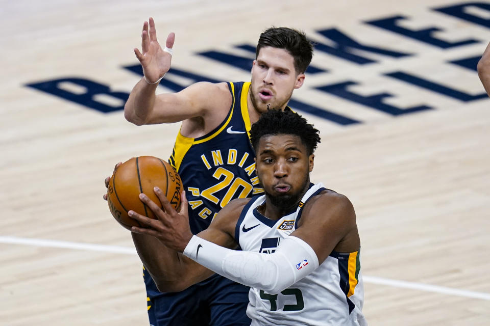 Utah Jazz guard Donovan Mitchell (45) makes a pass in front of Indiana Pacers forward Doug McDermott (20) during the first half of an NBA basketball game in Indianapolis, Sunday, Feb. 7, 2021. (AP Photo/Michael Conroy)