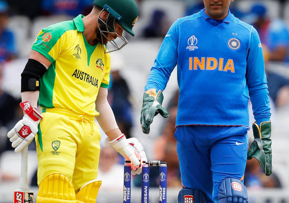 David Warner and MS Dhoni inspect the pesky bails. (Photo by ADRIAN DENNIS/AFP/Getty Images)