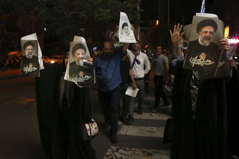 伊朗民眾拿著候選人萊希的相片在德黑蘭街頭表達支持。（美聯社）
