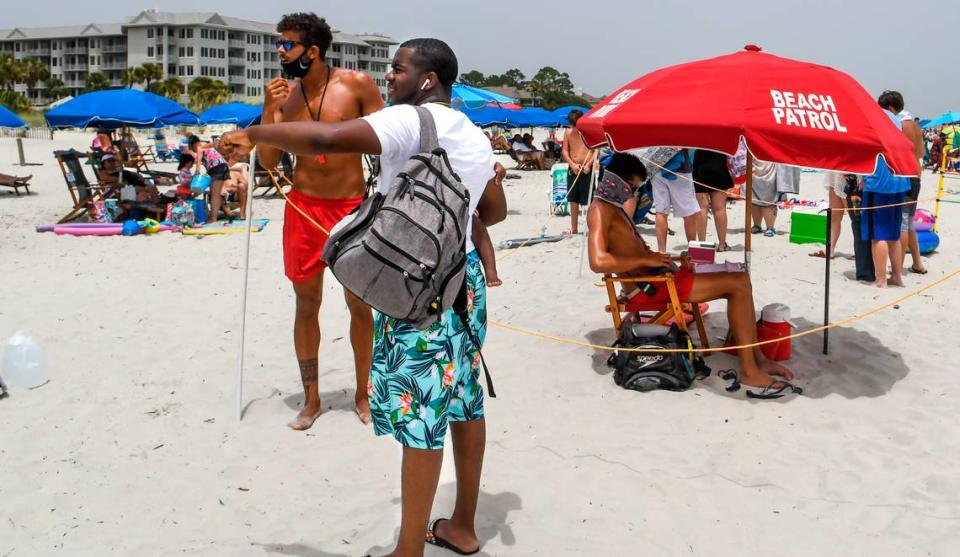 A beachgoer asks a Shore Beach Service lifeguard about a rental on Saturday, June 27, 2020 on the beach of Hilton Head Island. Lifeguards must wear a face covering while on the beach and they maintain social distancing by marking off their lifeguard stands with a boundary rope.