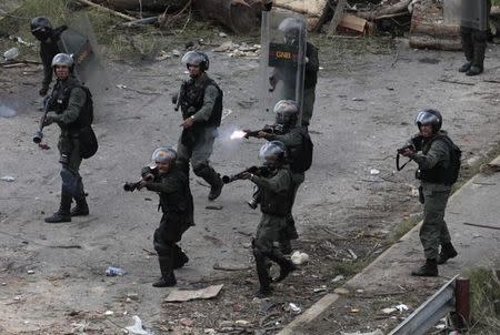 Security forces members point their weapons as one fires as they face off against demonstrators while clashes break out while the Constituent Assembly election is being carried out in Caracas, Venezuela, July 30, 2017. REUTERS/Marco Bello