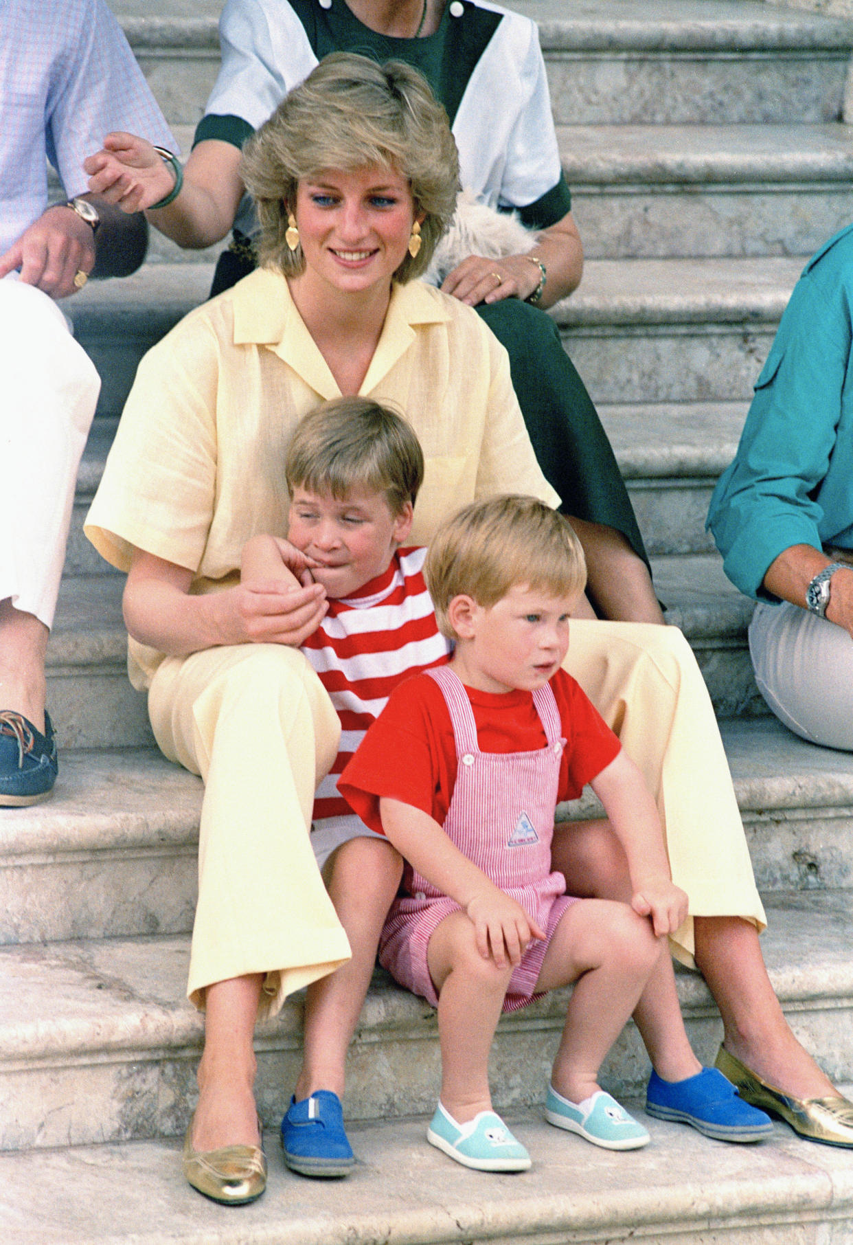 Diana, Princess of Wales, smiles as she sits with her sons, Princes Harry, foreground, and William, on the steps of the Royal Palace on the island of Mallorca, Spain, Aug. 9, 1987. (John Redman/AP)