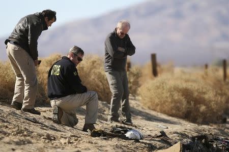 Investigators from the NTSB look at wreckage from the crash of Virgin Galactic's SpaceShipTwo near Cantil, California November 2, 2014. REUTERS/David McNew