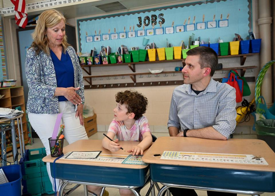 Framingham second grader Isaac Ouellette sits at his desk as his father, Michael, visits the classroom of retiring Dunning Elementary School teacher Colleen Gazard, left, June 15, 2022. Father and son both had Gazard as a teacher, Michael as a first grader during Gazard's first year at Dunning, and Isaac as a second grader this year, her last as a teacher at Dunning.