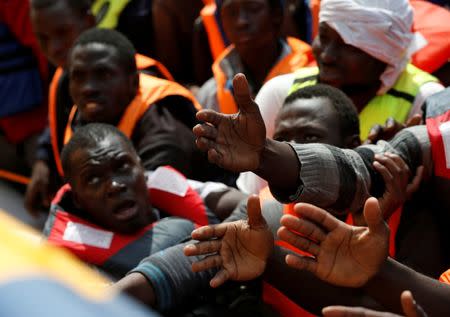 Migrants in a dinghy reach out towards Migrant Offshore Aid Station (MOAS) rescuers on board of the MOAS ship Topaz Responder around 20 nautical miles off the coast of Libya, June 23, 2016. Picture taken June 23, 2016. REUTERS/Darrin Zammit Lupi