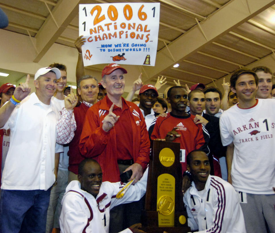 FILE - In this May 11, 2006, file photo, Arkansas coach John McDonnell, center underneath sign, poses with the team after the team received the national championship trophy at the NCAA Division I indoor track and field championships in Fayetteville, Ark. Also pictured are team members Peter Kosgei, bottom left, Said Ahmed, bottom right, and Josphat Boit, right of McDonnell. John McDonnell, the track and field coach who set a gold standard for excellence at Arkansas during his 36 years at the school, has died. He was 82. He died Monday night, June 7, 2021, according to a family statement released by the university. (AP Photo/April L. Brown, File)