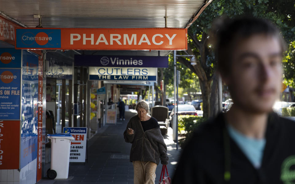 Sam Ware, 22, right, walks by the pharmacy where he used to get some of his opioid prescriptions filled in The Entrance, Central Coast, Australia, Thursday, July 25, 2019. The drugs were cheap. Most medications in Australia are government subsidized. For people like Sam who have concession cards _ those who are older, or on low incomes, or have a disability _ the out-of-pocket cost is just 6.50 Australian dollars (US$4.50) per prescription. (AP Photo/David Goldman)