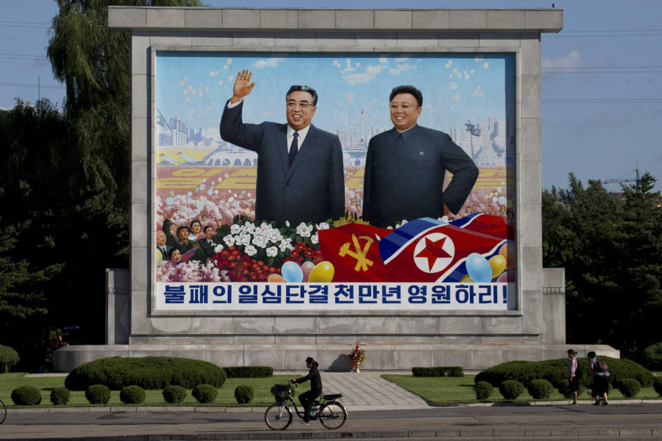 A woman cycles past a mural showing late North Korean leaders Kim Il Sung and Kim Jong Il as the capital prepares for the 70th anniversary of North Korea's founding day in Pyongyang, North Korea, Friday, Sept. 7, 2018. North Korea will be staging a major military parade, huge rallies and reviving its iconic mass games on Sunday to mark its 70th anniversary as a nation. (AP Photo/Ng Han Guan)