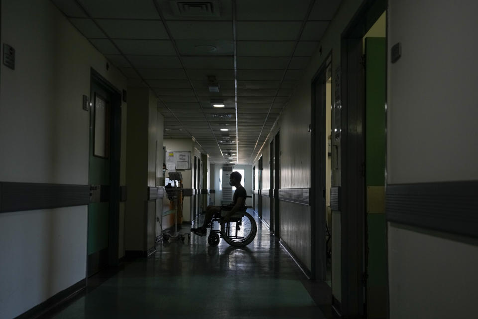 A patient attends in a corridor of the government-run Rafik Hariri University Hospital during a power outage in Beirut, Lebanon, Wednesday, Aug. 11, 2021. Many private hospitals, who offer 80% of Lebanon's medical services, are shutting down because of lack of resources or turning away patients who can't pay. (AP Photo/Hassan Ammar)