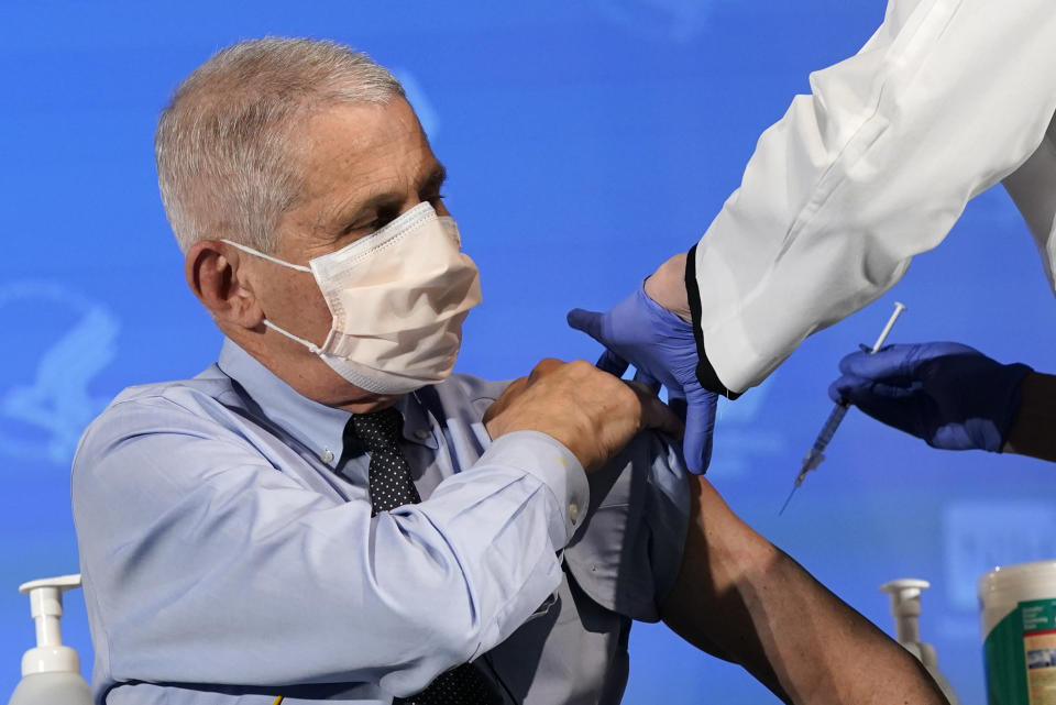 Fauci, wearing a mask and with his left sleeve rolled up, gets a COVID-19 shot.