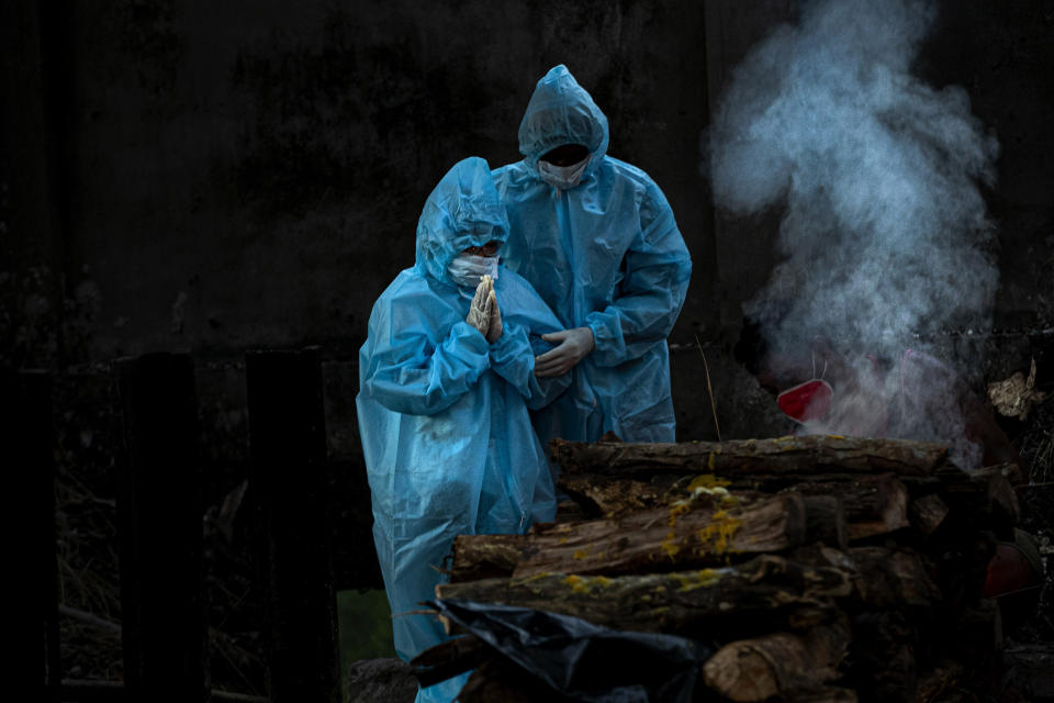 A 9-year-old boy, left, wearing personal protective equipment performs rituals during the cremation of his father who died of COVID-19 in Gauhati, India, Monday, Sept. 28, 2020. (AP Photo/Anupam Nath)